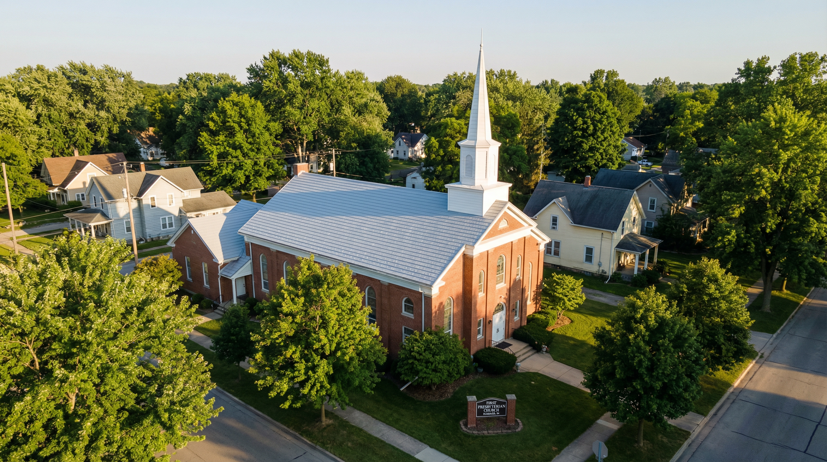 Church building in Elkhart, Indiana with a bright white coated roof and steeple surrounded by trees